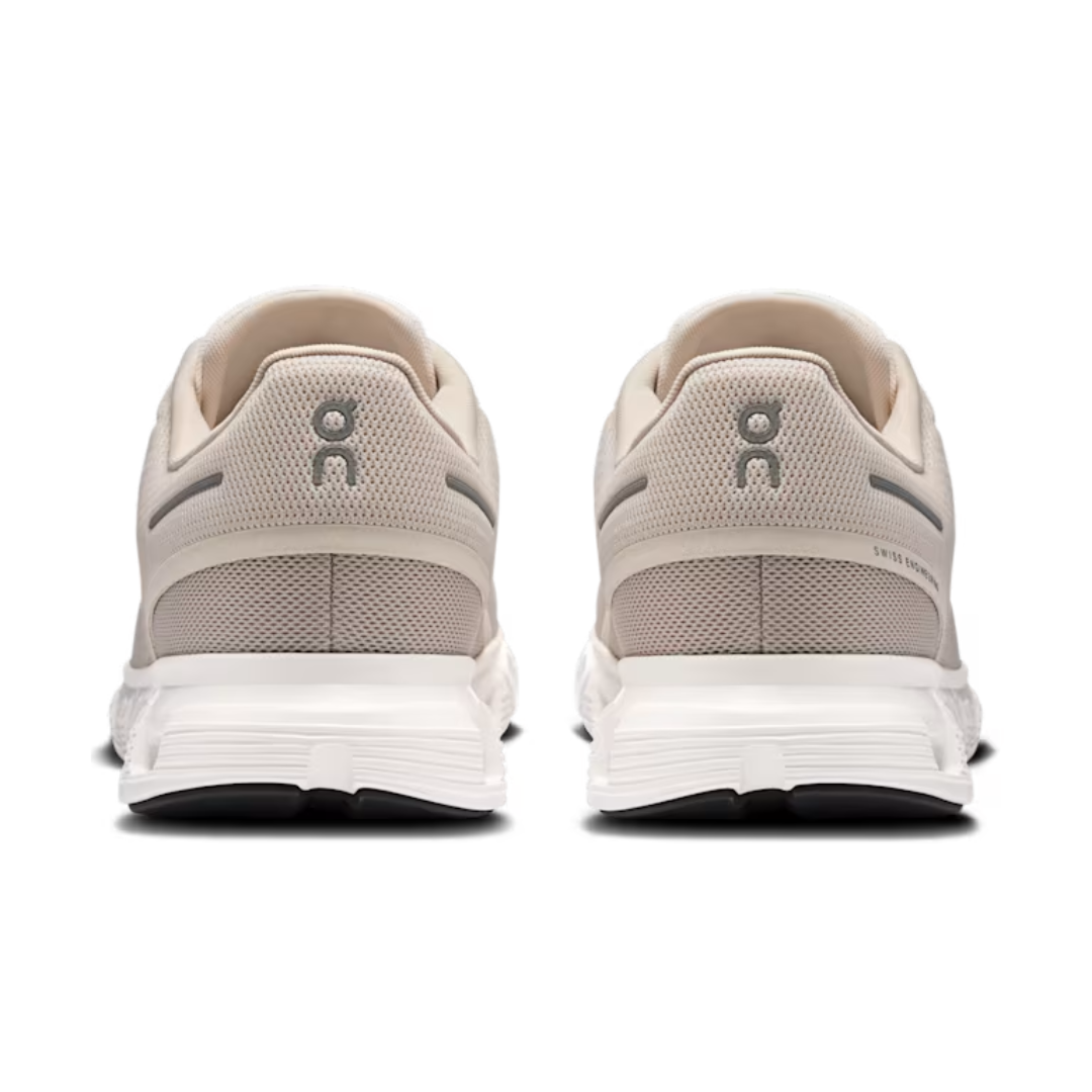 Pair of beige running shoes with white soles on a white background